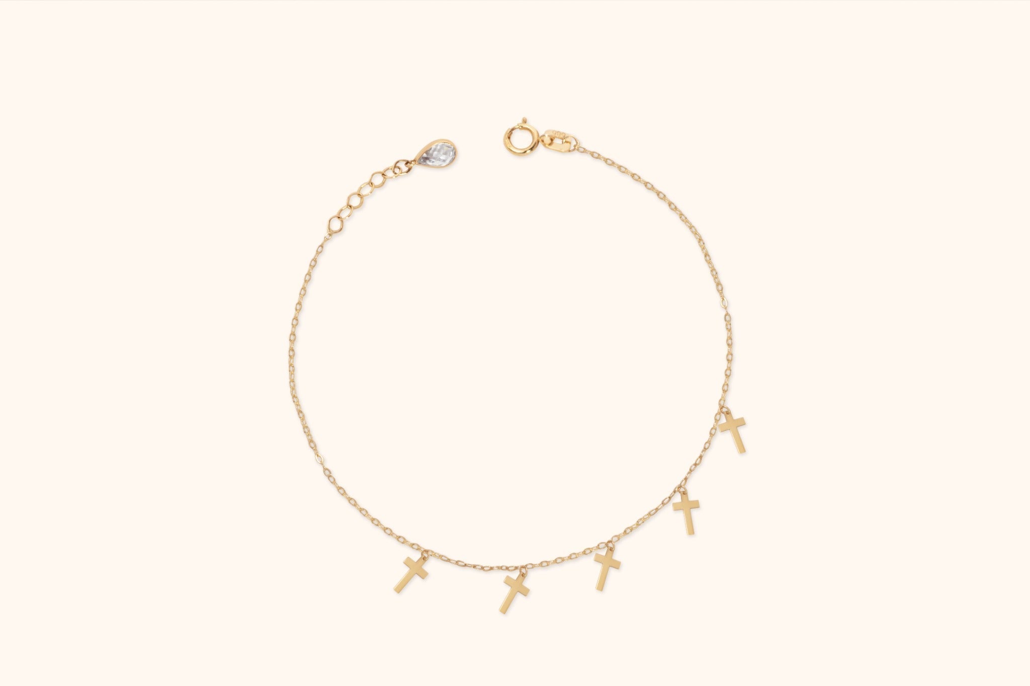 Fine gold-colored chain bracelet with five dangling cross charms, a round clasp, and an extension chain with a teardrop-shaped charm.