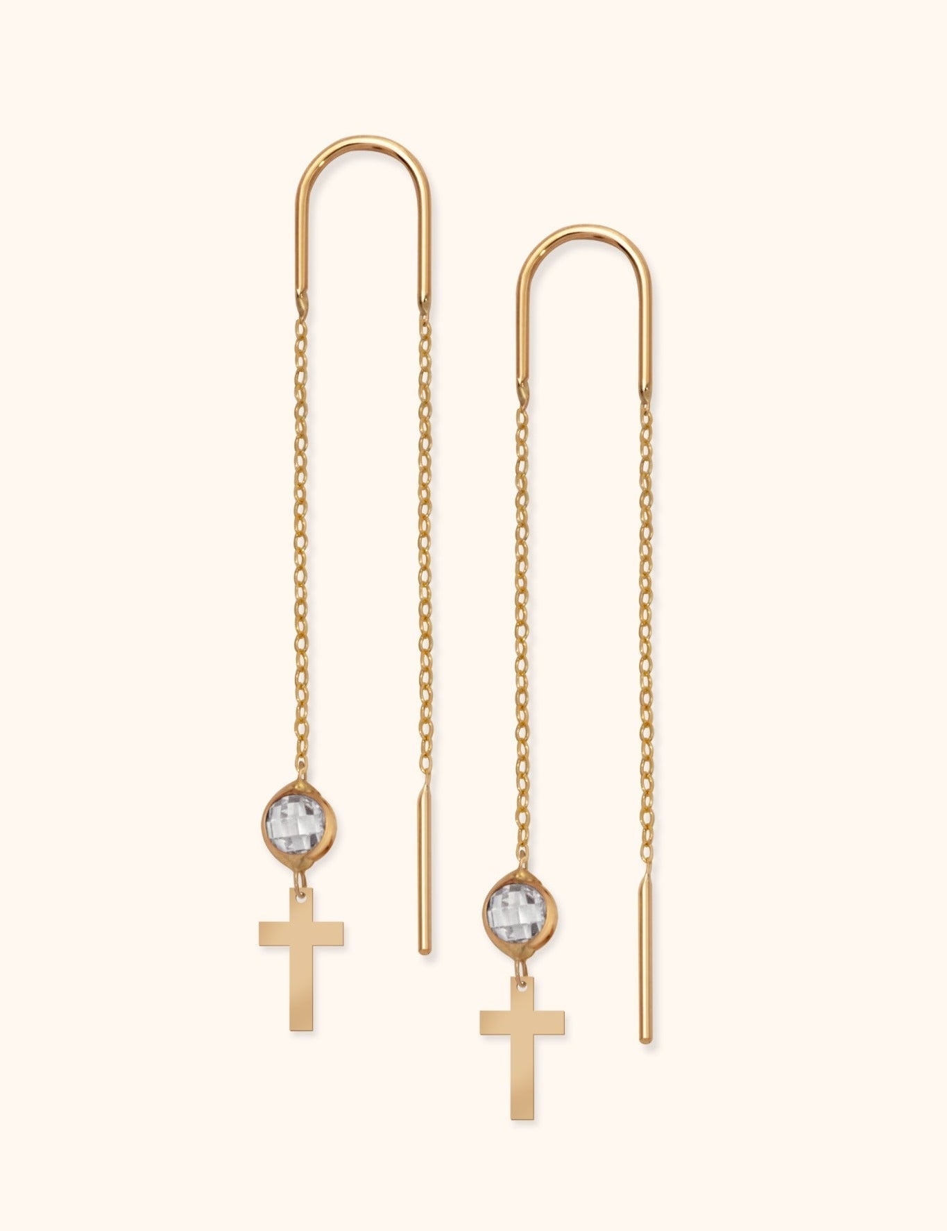 Pair of gold-tone threader earrings with long chains, clear faceted beads, and flat cross charms on a cream background.