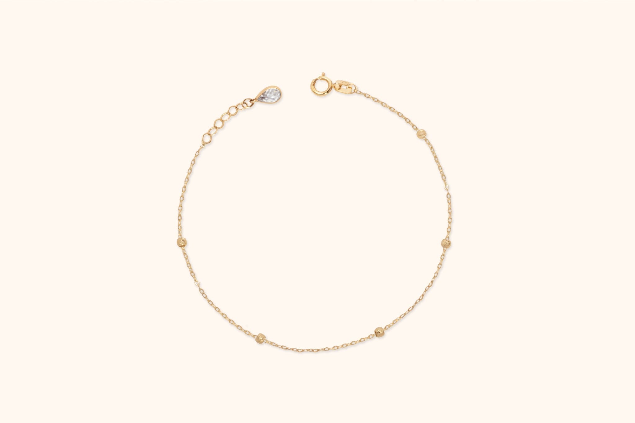 Fine gold-toned chain bracelet with five spaced textured beads, a round clasp, extension links and a teardrop-shaped end charm.