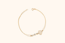 Gold-tone double-chain bracelet with an openwork lotus, three clear faceted accents, a round clasp and extension links.