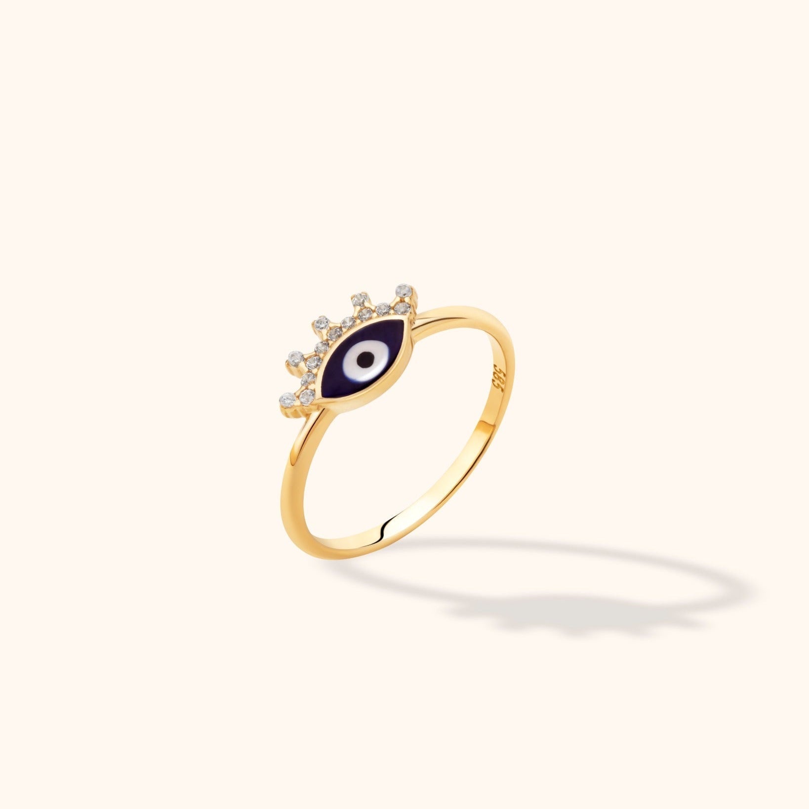 Gold-colored slim ring with a dark blue, white and black eye motif and clear round accents along its upper edge.