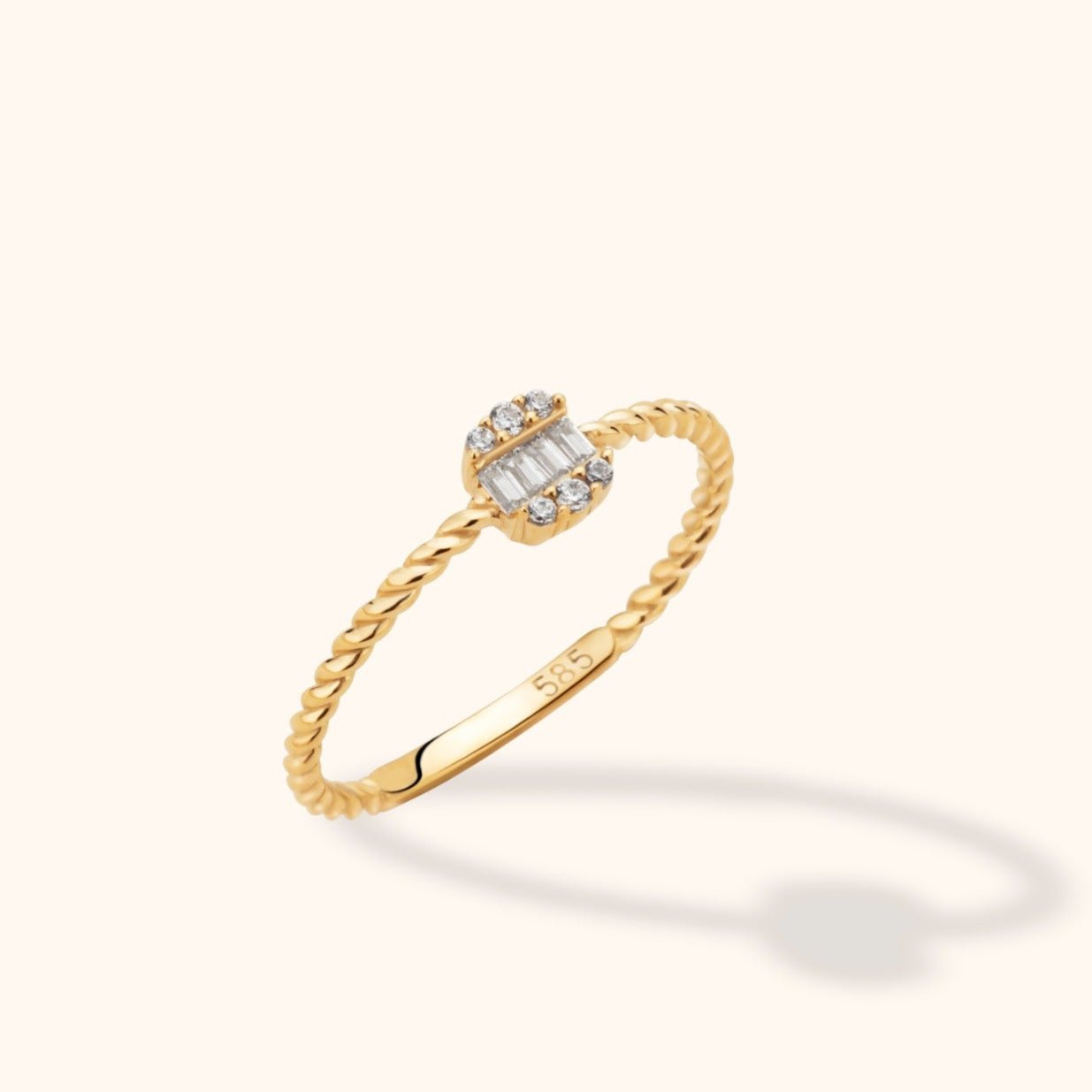 Gold-toned ring with a twisted rope-style band and a rectangular cluster of clear baguette-shaped and round stones.