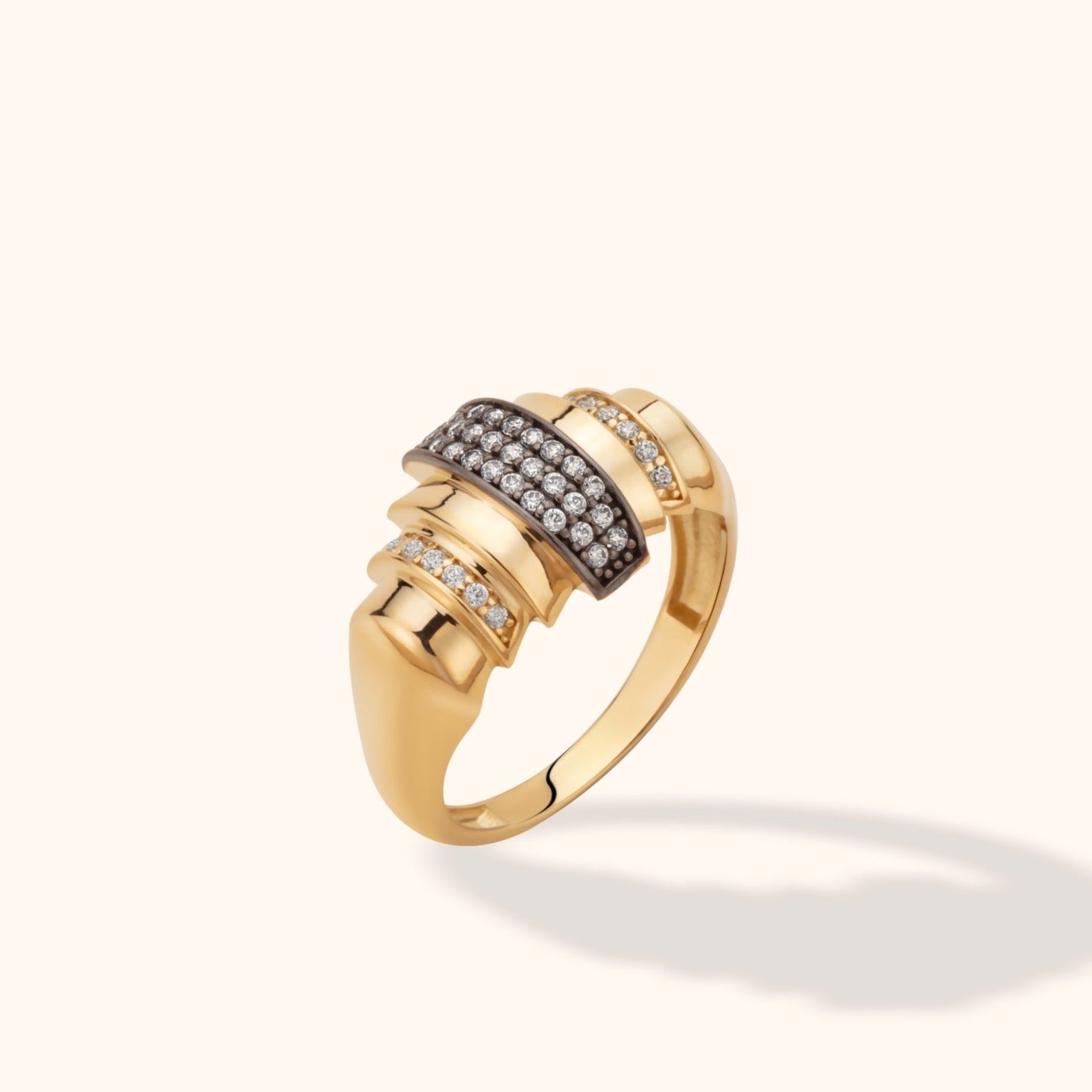 Gold-toned ring with stepped polished ridges, a dark central panel of clear round stones, and smaller stone rows on either side.