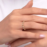 Close-up of a woman's hand wearing a 14K gold ring featuring horizontally set baguette-cut stones linked with gold bead details, complemented by a delicate gemstone bracelet.