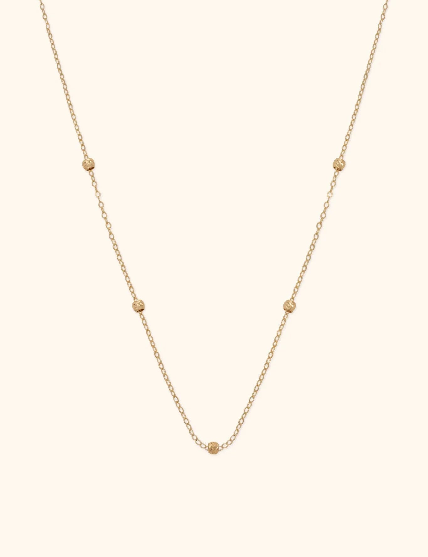 14K gold necklace with small textured bead accents on fine chain