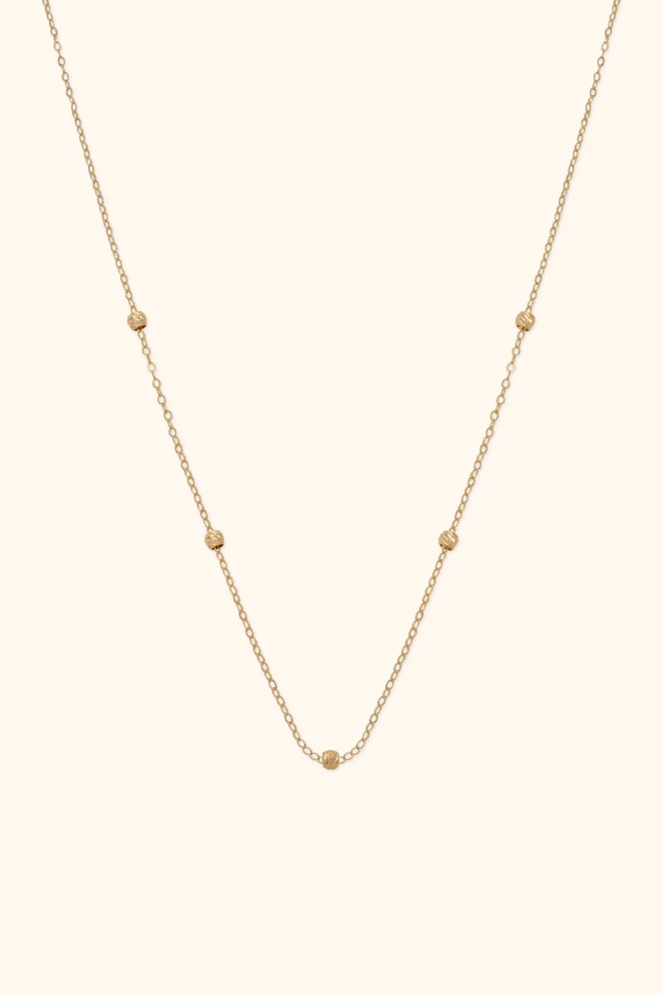 14K gold necklace with small textured bead accents on fine chain