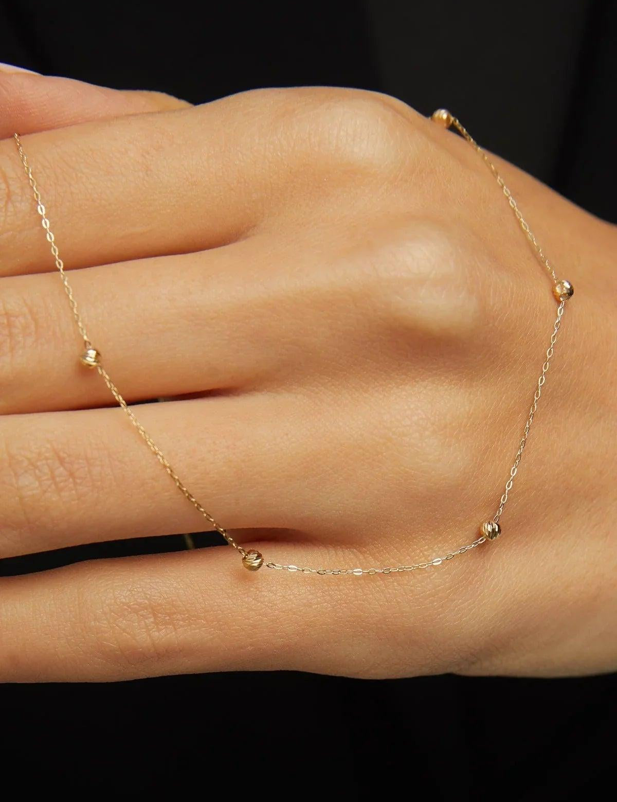 Minimalist 14K solid gold necklace with round beads spaced along a fine chain,