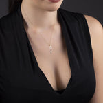 14K gold necklace with a key-shaped pendant featuring a four-leaf clover design, styled on magenta satin fabric.