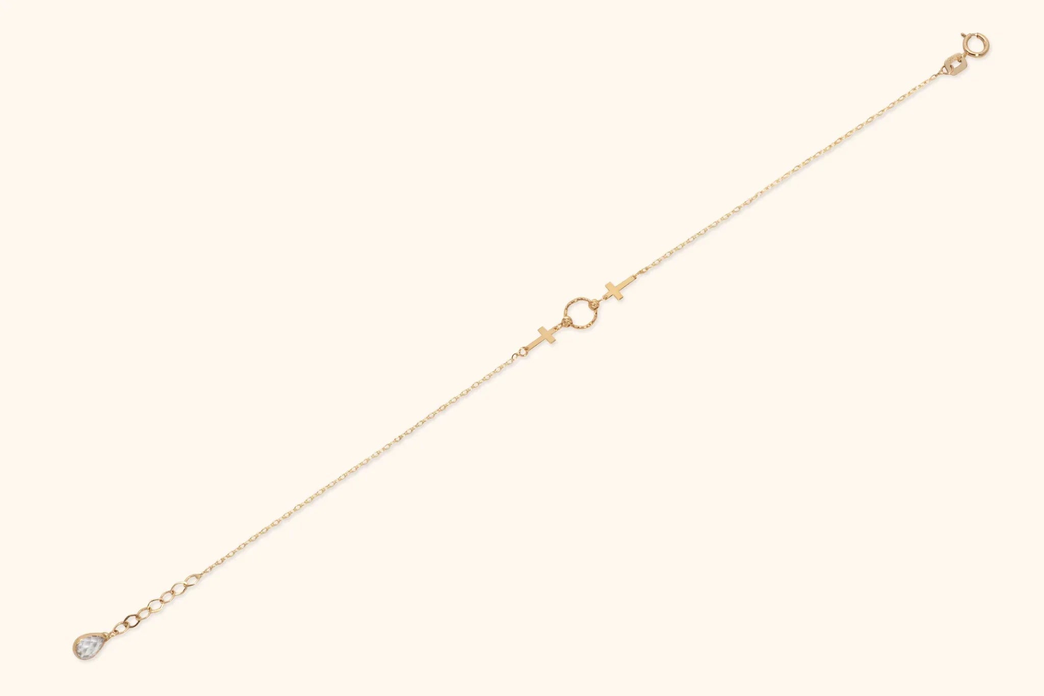 14K gold twin cross charm bracelet with center twisted circle on cream background