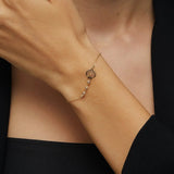 Elegant 14K gold bracelet with a cut-out seashell charm and faceted crystal beads, styled on rich emerald satin
