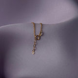 Elegant 14K gold bracelet with a cut-out seashell charm and faceted crystal beads, styled on rich emerald satin