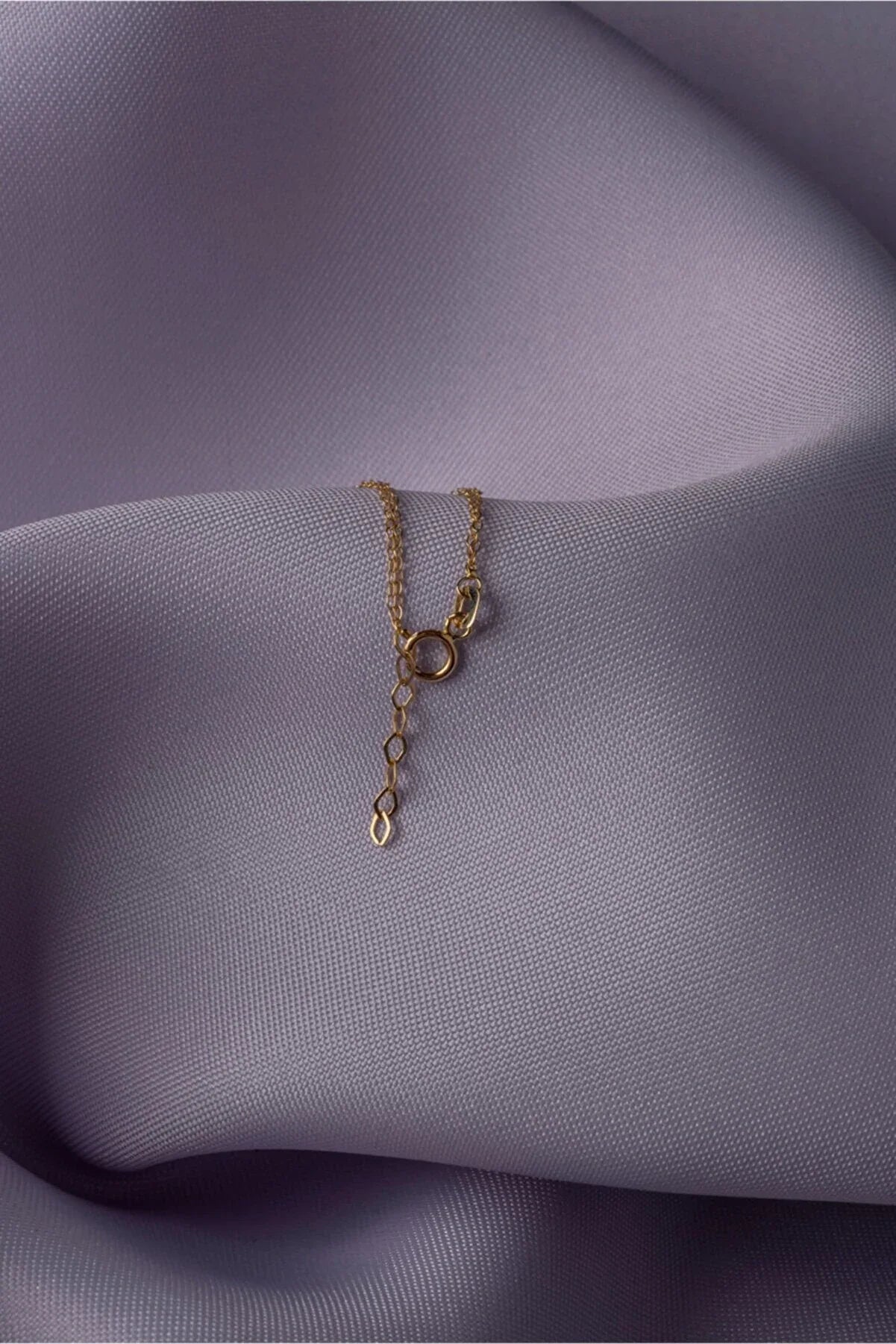 Elegant 14K gold bracelet with a cut-out seashell charm and faceted crystal beads, styled on rich emerald satin