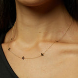 Minimalist 14K gold bracelet with flying bird charms on model’s