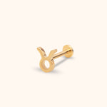Gold-colored Taurus symbol stud earring with a straight post and round flat back, shown at an angle on a cream background.