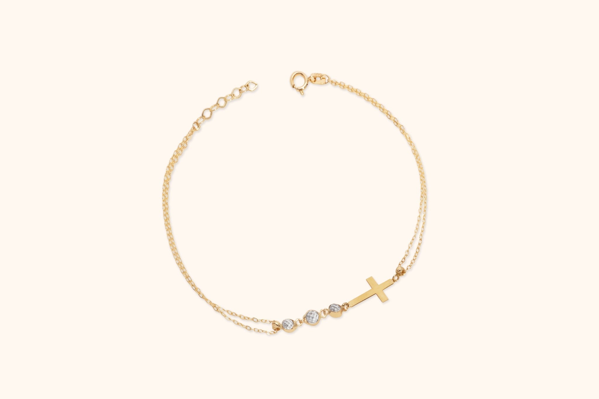 Gold-toned double-chain bracelet with a sideways cross, three round faceted accents, a ring clasp and extension links.