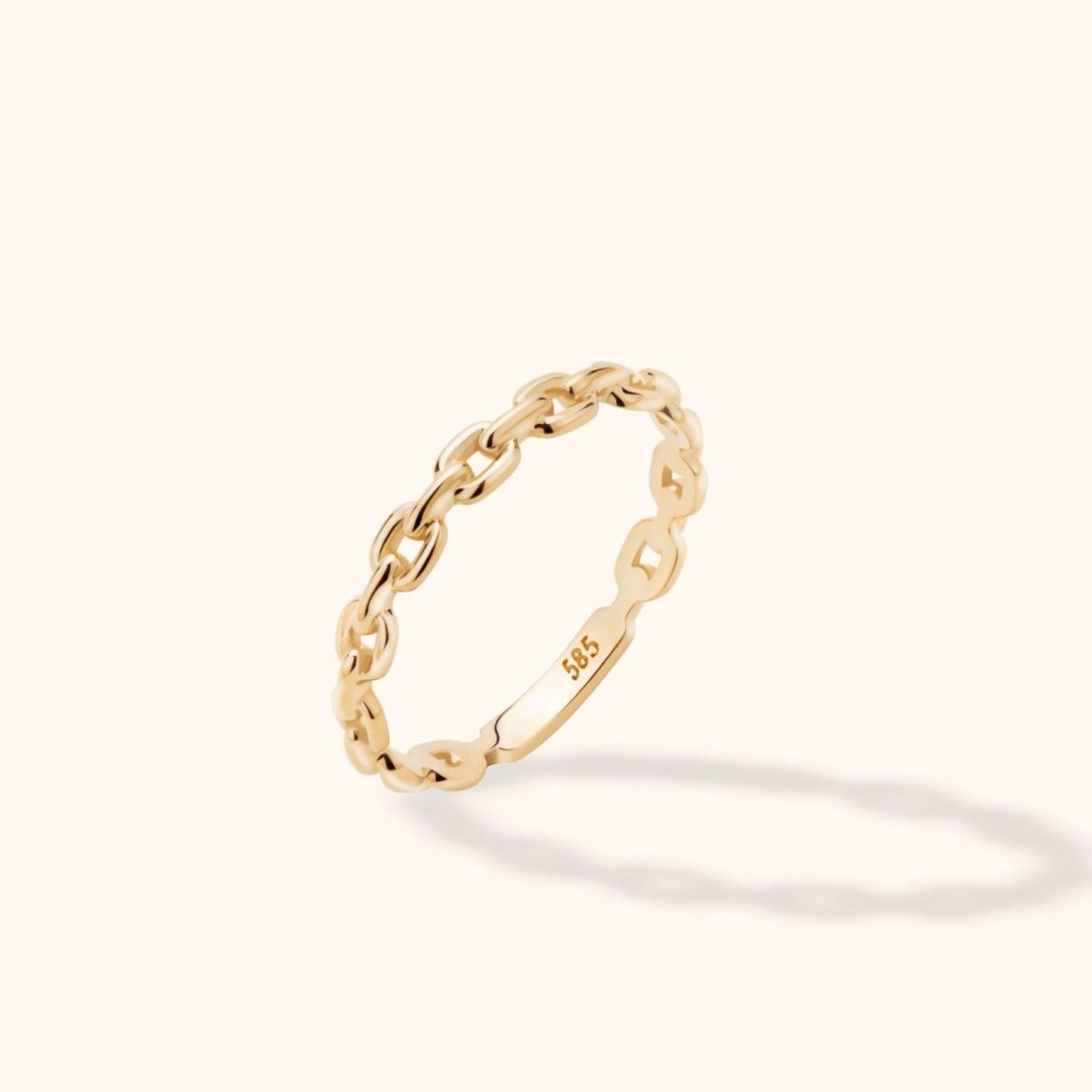 Slim gold-toned ring with oval chain links and a smooth section stamped 585, shown at an angle on a cream background.