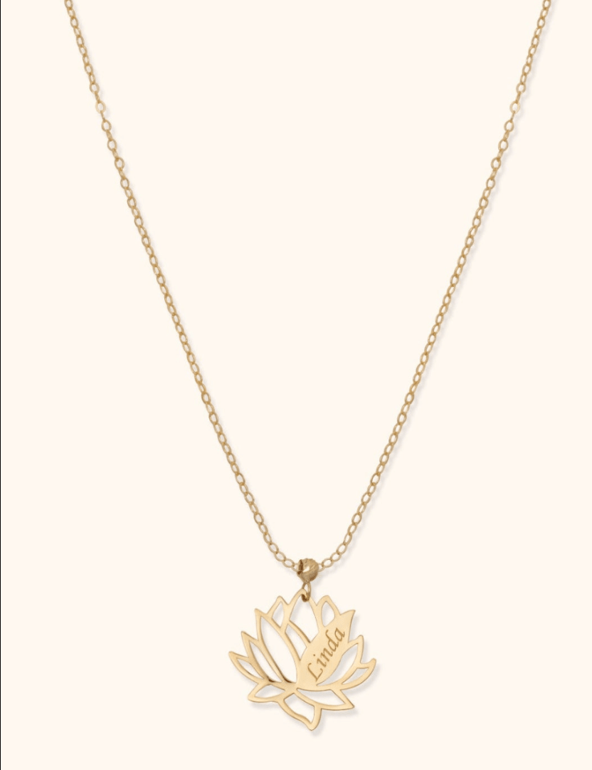 Gold-colored chain necklace with an openwork lotus flower pendant engraved with the name Linda on a cream background.