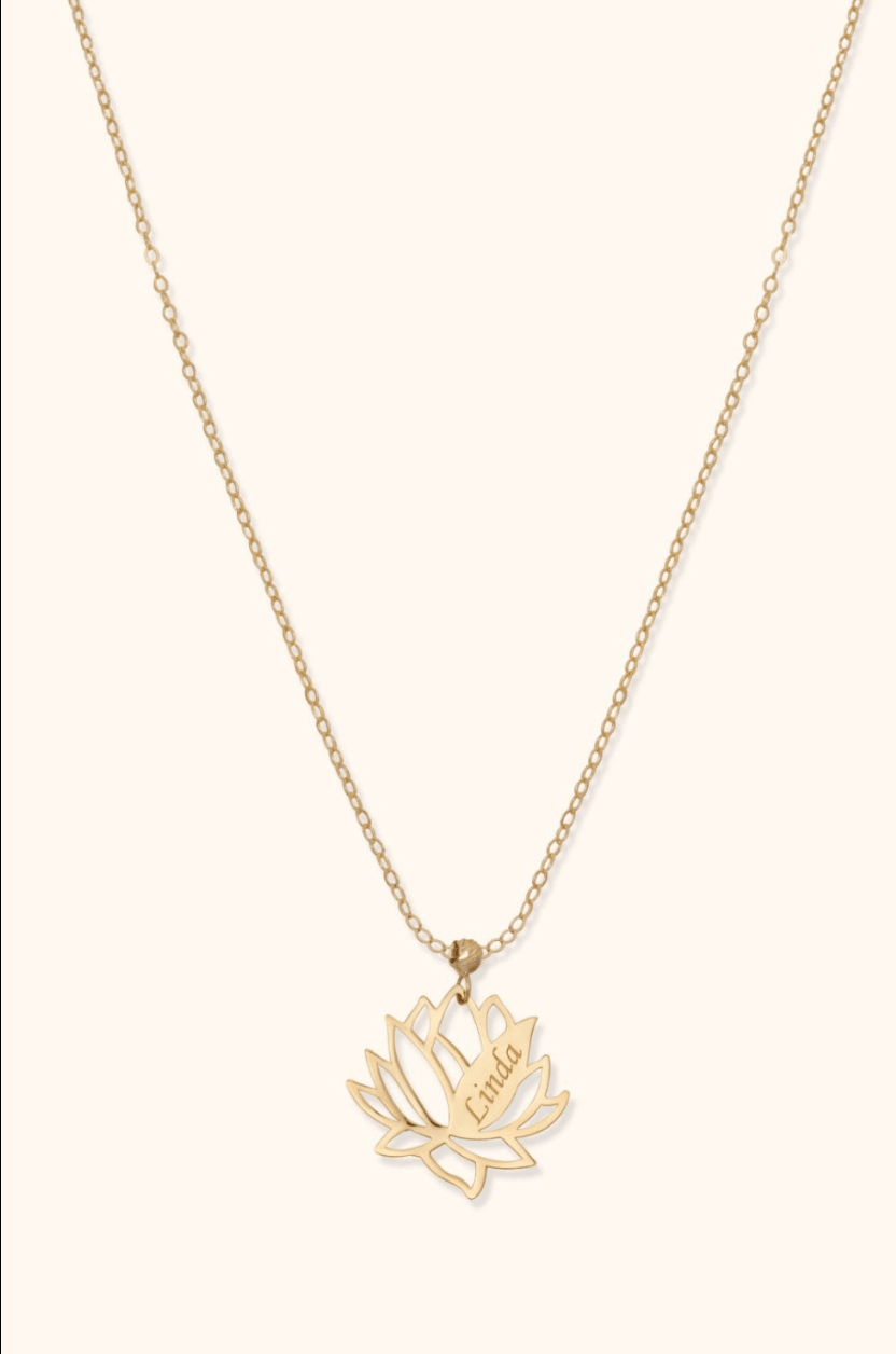 Gold-colored chain necklace with an openwork lotus flower pendant engraved with the name Linda on a cream background.