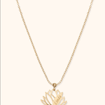 Gold-colored chain necklace with an openwork lotus flower pendant engraved with the name Linda on a cream background.