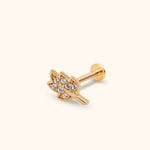 Gold-toned leaf-shaped stud earring with clear round accents, a straight post and a flat disc back on a cream background.