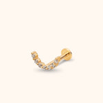 Gold-toned piercing stud with a curved row of clear round stones, a straight post and a flat disc back on a cream background.
