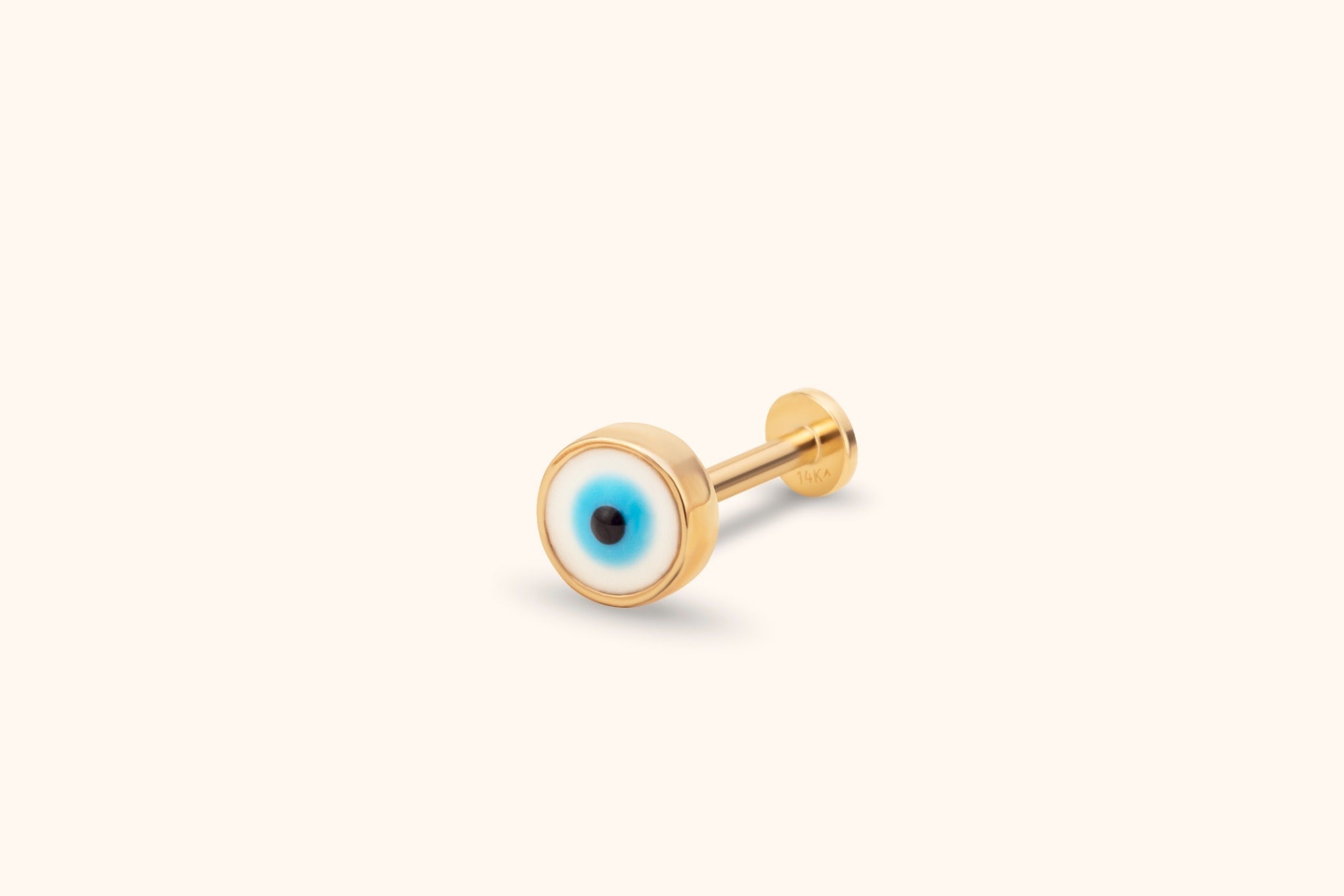Gold-toned stud with a round white, blue and black evil eye face, straight post and flat disc back on a cream background.