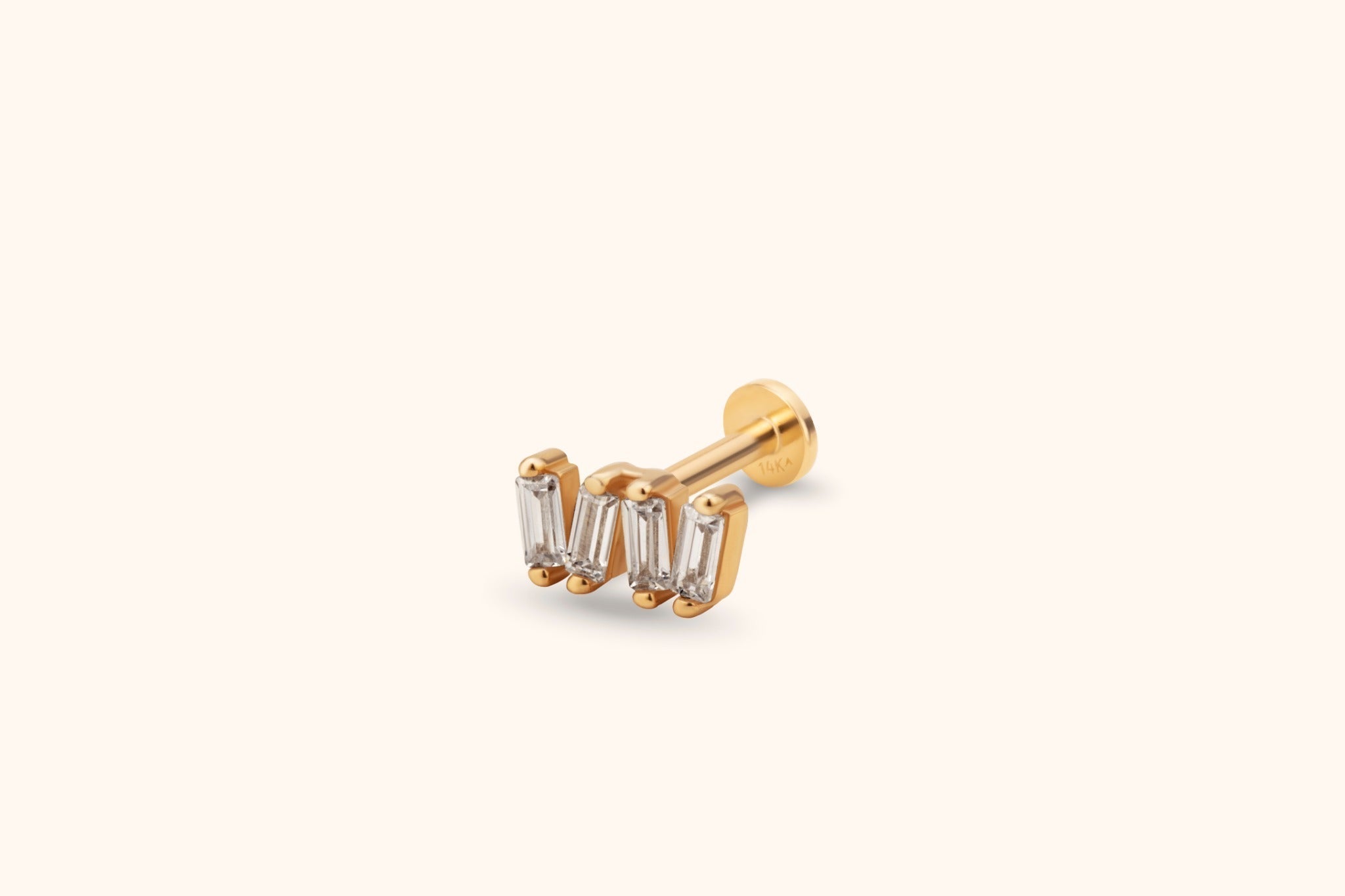 Gold-colored flat-back stud with four clear rectangular stones in a gently curved row, shown at an angle on a cream background.