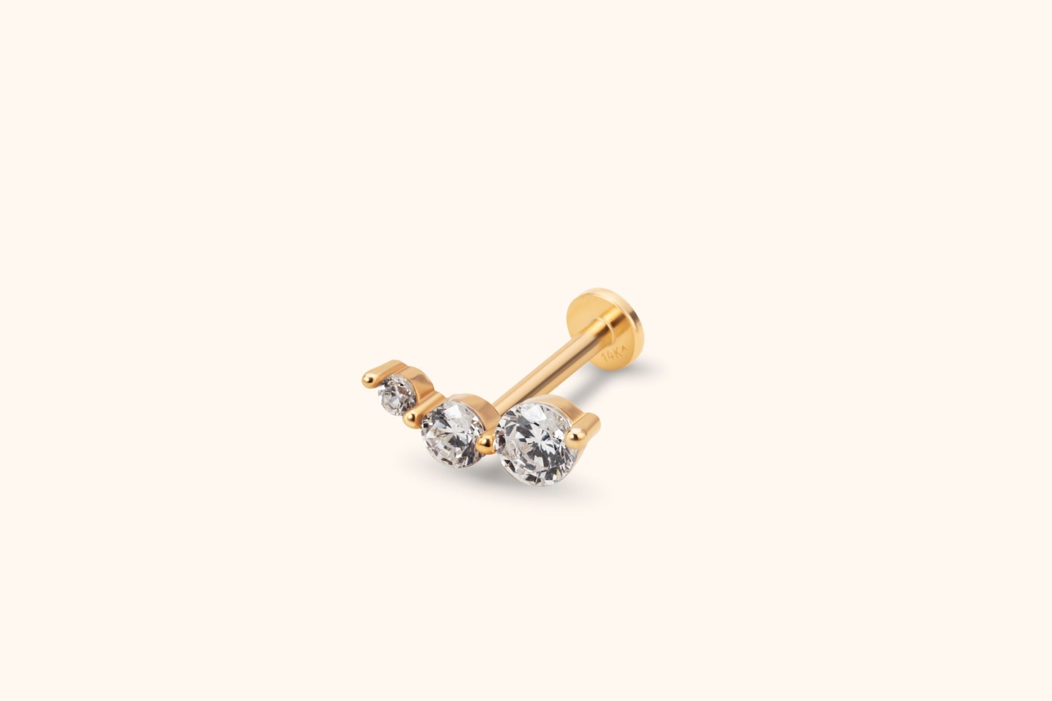 Gold-toned piercing stud with three clear round stones in increasing sizes, a straight post and a flat circular back.