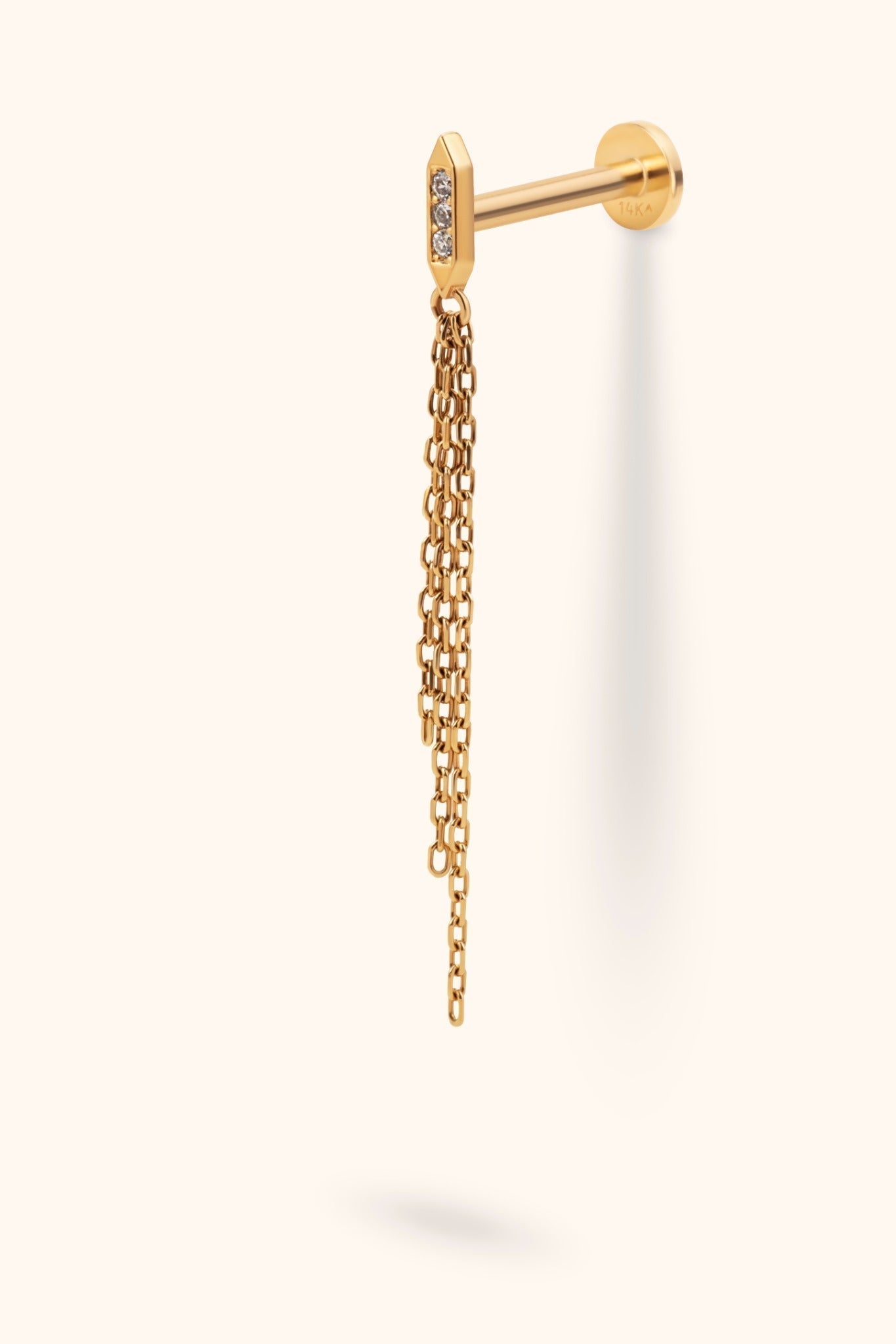 Gold-tone piercing stud with three clear accents on a slim bar, dangling chains of varied lengths, and a round flat back.