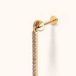 Gold-tone stud earring with a flat disc back and a long dangling bar lined with small, clear round stones.