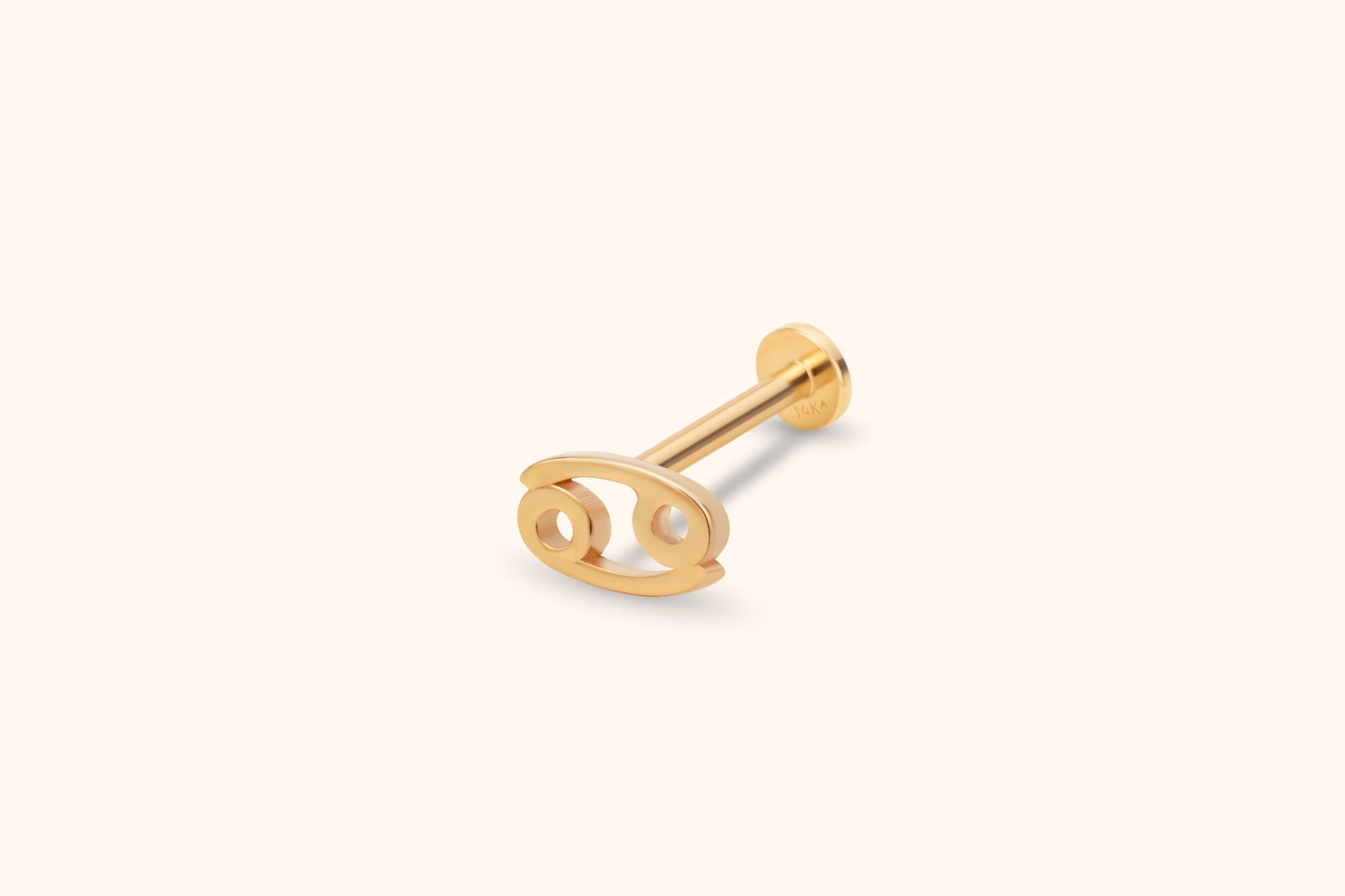 Gold-toned Cancer zodiac stud with an openwork symbol, straight post and round flat back, shown diagonally on a cream background.