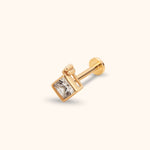 Gold-toned stud earring with a clear square faceted accent, straight post and round flat back, shown at an angle on a cream background.
