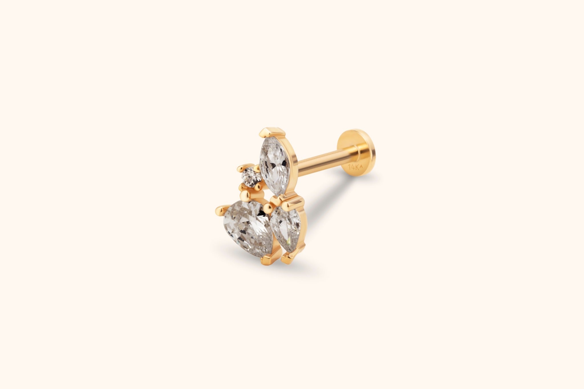 Gold-tone flat-back stud with a cluster of clear marquise, pear-shaped and round stones, shown at an angle on a cream background.