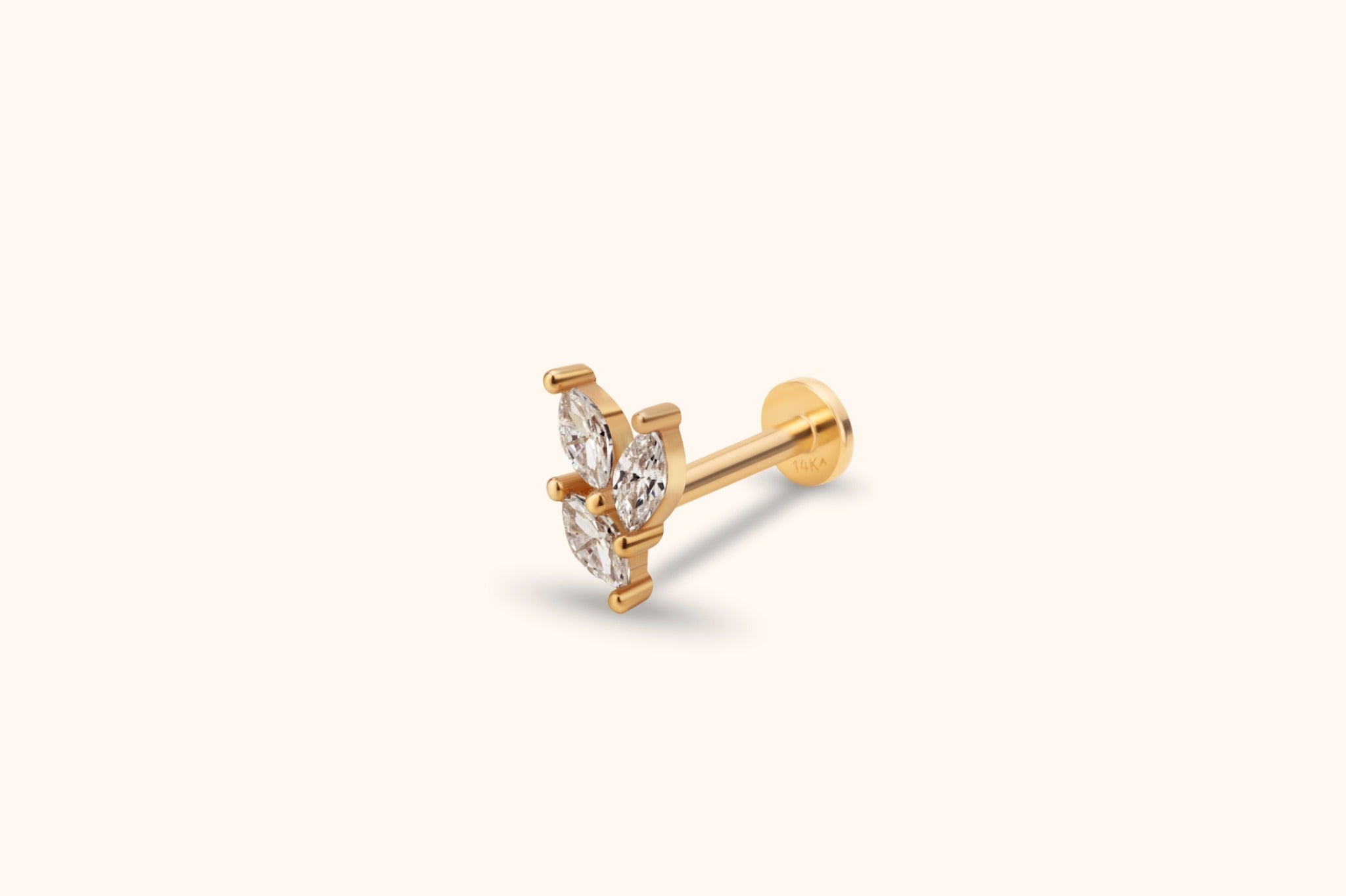 Gold-toned stud with three clear marquise-shaped accents in a cluster, a straight post and a flat round back on a cream background.
