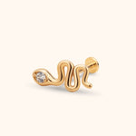 Gold-toned snake stud earring with a wavy body, clear faceted detail at the head, and a round flat back on a cream background.