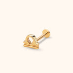 Gold-colored Libra symbol stud with a straight post and flat round back, shown at an angle on a cream background.
