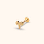 Gold-toned Aries symbol stud with a straight post and round flat back, shown at an angle on a pale cream background.