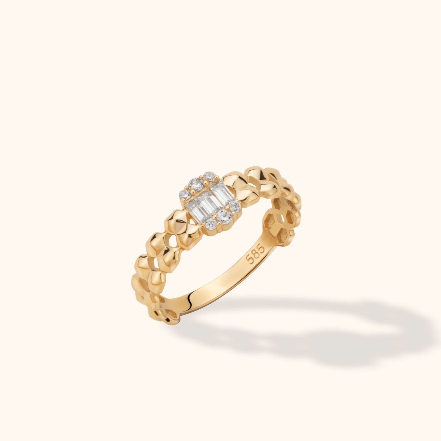 Gold-colored ring with an open geometric link band and rectangular clear stones bordered by round clear stones.