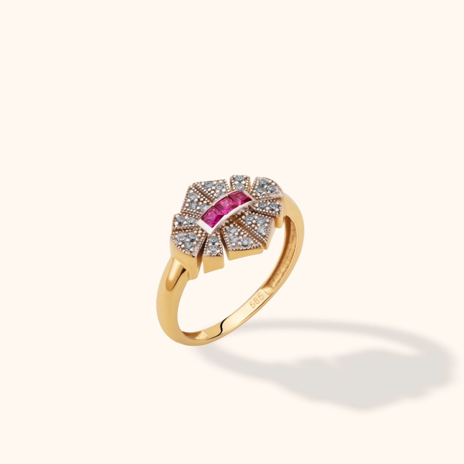 Gold-toned ring with a row of square pink stones and a segmented sunburst face dotted with small clear stones.