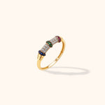Gold-tone ring with rows of clear stones, blue, green and pink stone bands, and ridged accents on a pale background.