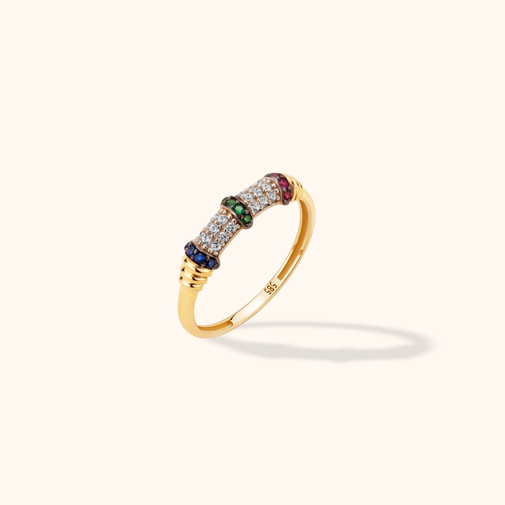 Gold-tone ring with rows of clear stones, blue, green and pink stone bands, and ridged accents on a pale background.