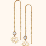 Pair of gold-colored threader earrings with fine chains, openwork lotus charms and round, clear faceted accents.