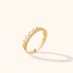Gold-toned ring with a crown-like edge of rounded bead tips and a row of clear stones, shown at an angle on a cream background.
