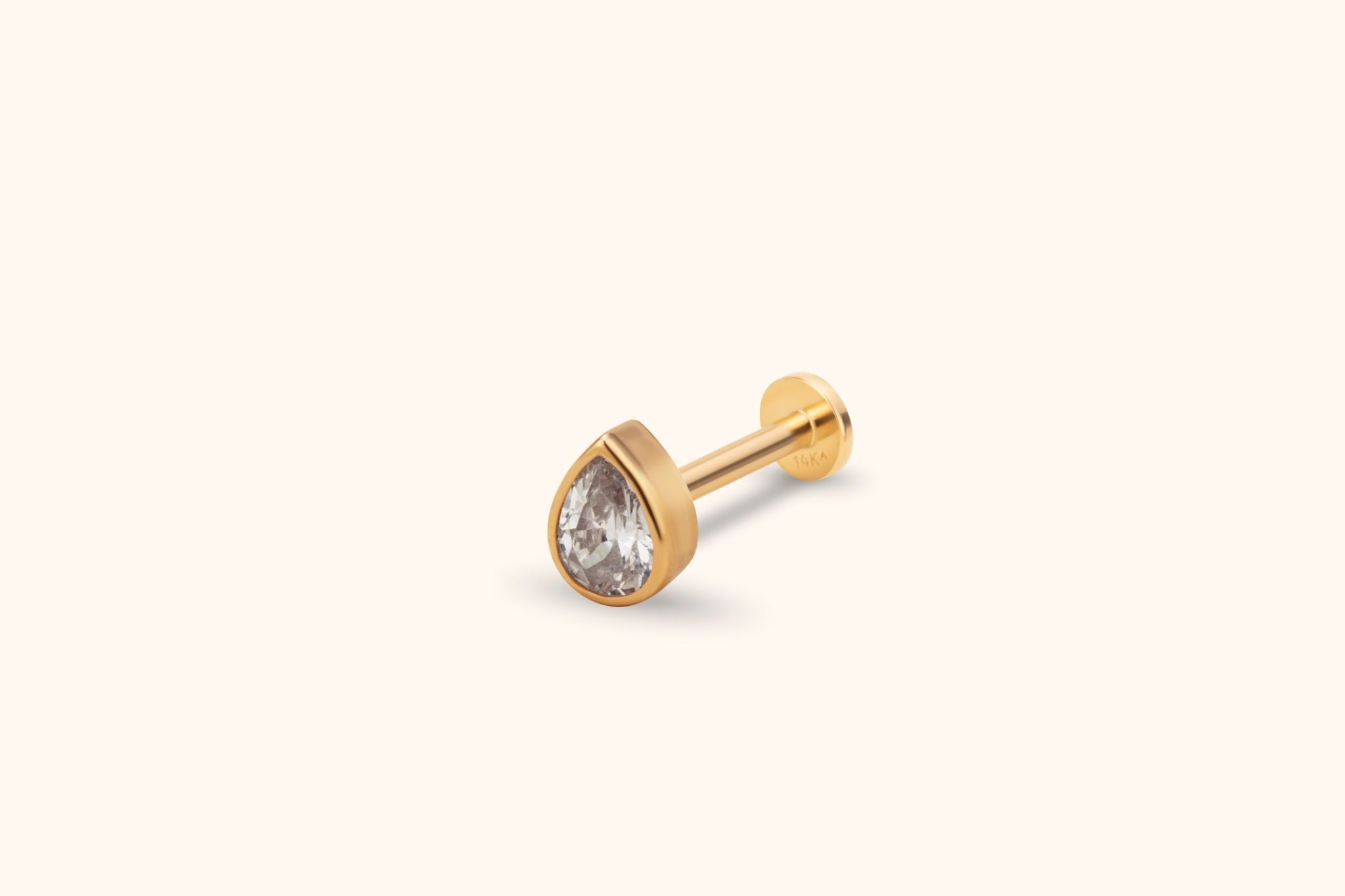 Gold-toned stud earring with a clear teardrop-shaped faceted stone, smooth bezel setting, straight post and flat round back.