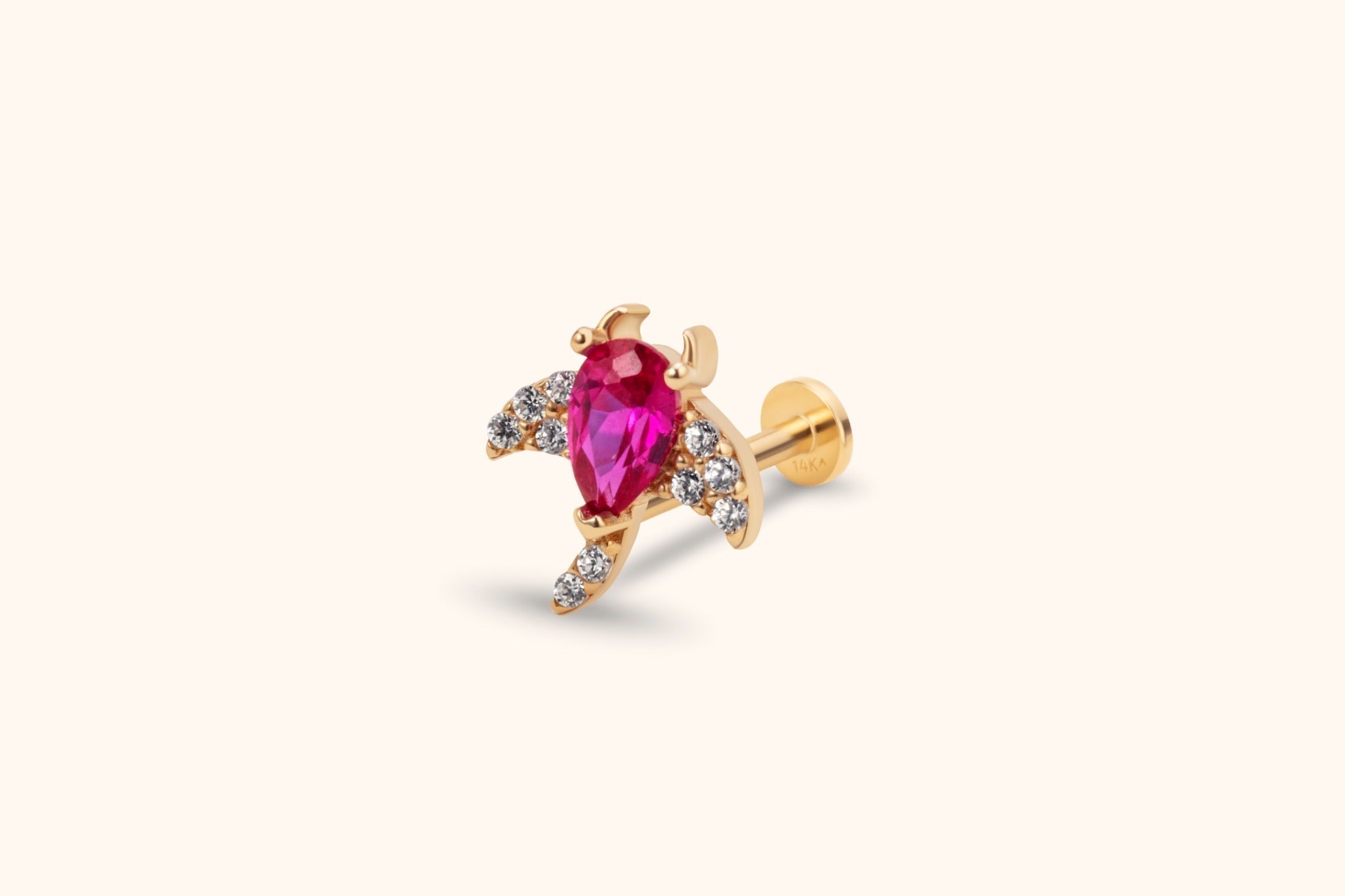 Gold-toned flat-back stud with a pear-shaped vivid pink center stone and small clear stones along curved, wing-like extensions.