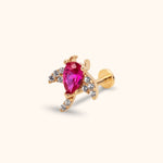 Gold-toned flat-back stud with a pear-shaped vivid pink center stone and small clear stones along curved, wing-like extensions.