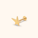 Gold-toned stud earring with a polished five-point star, straight post and round flat back on a pale cream background.