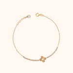 Gold-tone chain bracelet with a four-petal flower motif, clear round accents, an extender chain and a teardrop-shaped end charm.
