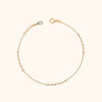 Gold-toned bracelet with fine chain sections, elongated links, a round clasp, and an extender ending in a teardrop-shaped charm.