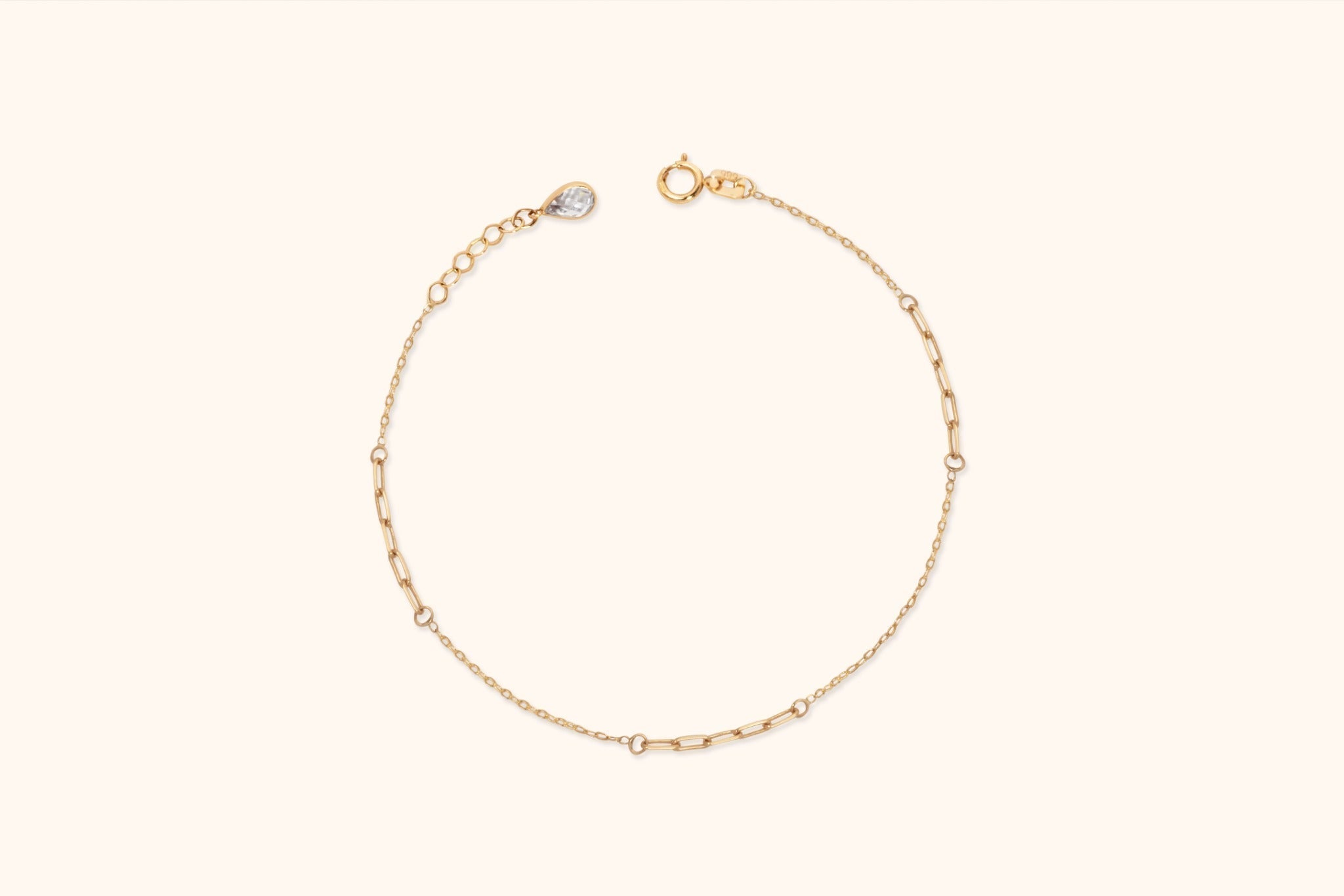 Gold-toned bracelet with fine chain sections, elongated links, a round clasp, and an extender ending in a teardrop-shaped charm.